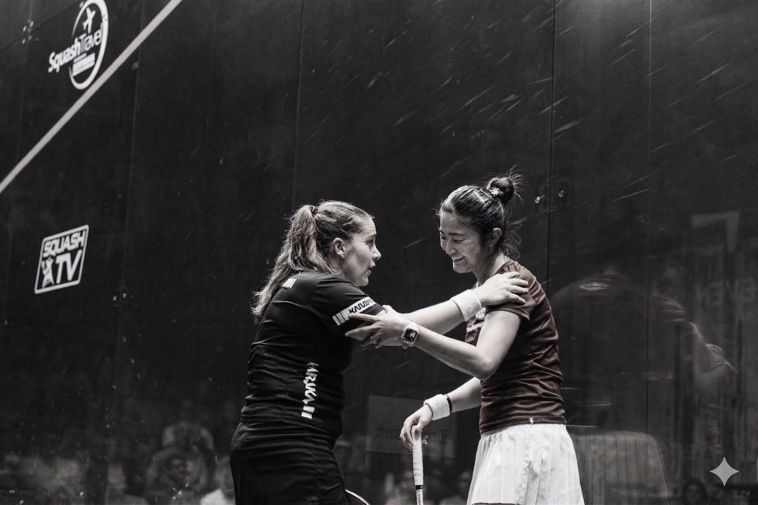 Two women squash players embracing on court after a match
